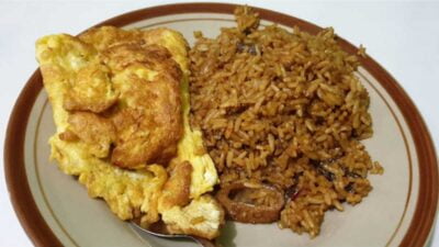 Sepiring nasi goreng babat khas Semarang dengan bumbu gongso pekat dan telur mata sapi di atas meja kayu.