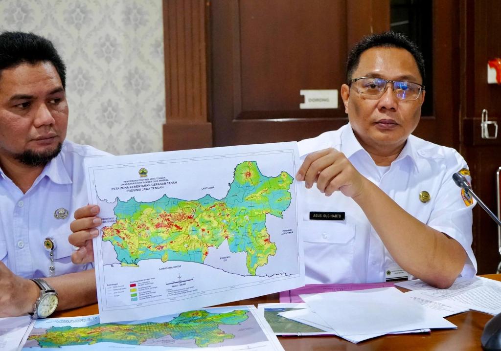 Kepala Dinas ESDM Jawa Tengah, Agus Sugiharto (kanan), yang mengenakan kemeja putih dan berkacamata, memegang dan menunjukkan "Peta Zona Kerentanan Gerakan Tanah Provinsi Jawa Tengah" yang menampilkan area berwarna merah, kuning, dan hijau. Ia didampingi seorang pria lain di sebelah kiri yang juga melihat ke arah peta tersebut dalam sebuah ruangan kantor.