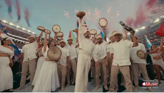 Penampilan Bad Bunny Super Bowl 2026 Halftime Show mengenakan setelan putih Zara di tengah set panggung ladang tebu Puerto Rico.