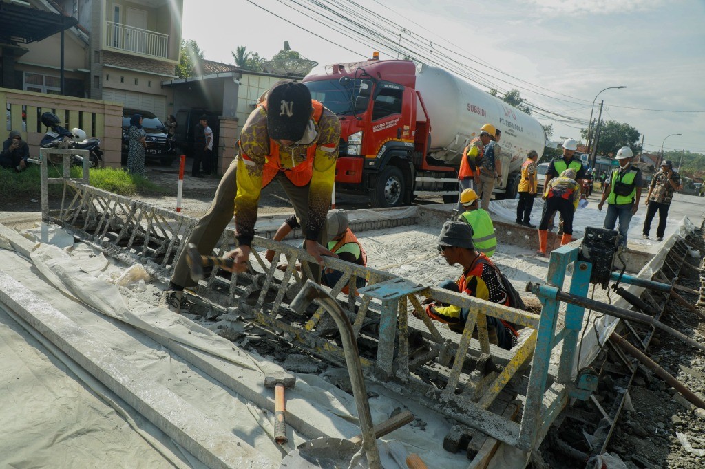 Pekerja Dinas PUPR Jawa Tengah sedang memperbaiki jalan provinsi yang rusak berat menggunakan alat berat pada tahun 2026.