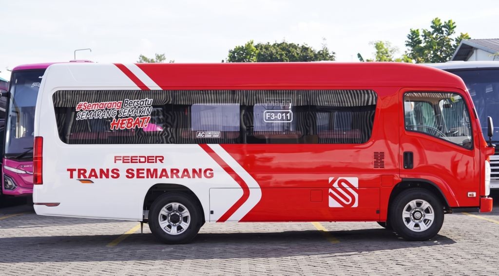Tampak samping mikrobus Feeder Trans Semarang berwarna merah dan putih dengan nomor F3-011 yang terparkir di area pool terbuka Kota Semarang.